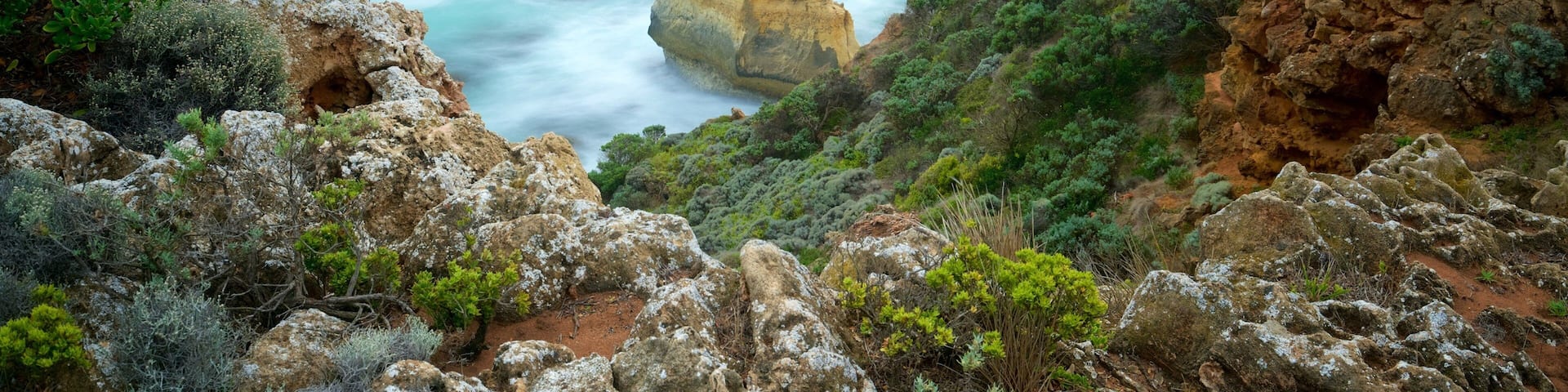 A coastal landscape with a sandy beach, turquoise waters, and rocky cliffs.