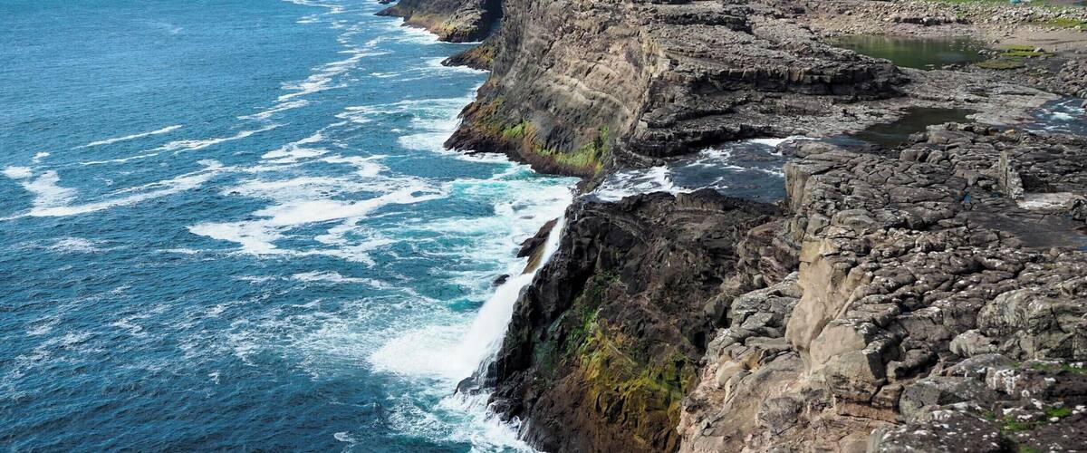 If you're not much of a hiker like me, yet still want to see some of the best views in the Faroe Islands, head out to Trรฆlanรญpa for a gentle hike that packs some serious coastal views. Go out as far as Bรธsdalafossur, which is a waterfall that empties out into the sea (can you spot it in this photo?).