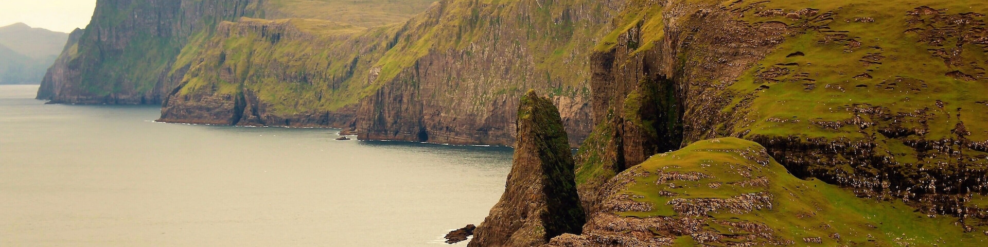 I took this photo at Sørvágsvatn in the Faroe Islands! This isn't a view of the lake itself or the iconic cliffs. But a view of lesser known cliffs right by the lake itself. And the body of water you see is the deep sea :). And the lake was to the right of me. To see both at the same time is a very cool sight, as well. But I like this close-up view the best. Can really get a feel of how otherworldly it is! As the classic views of the lake. I hiked about 4 KM to get to Sørvágsvatn and it was definitely worth it! Some other tourists as well, but not nearly as many as the peak of summer. I'm glad I went on that late August day! One of my favorite memories of 2018.
