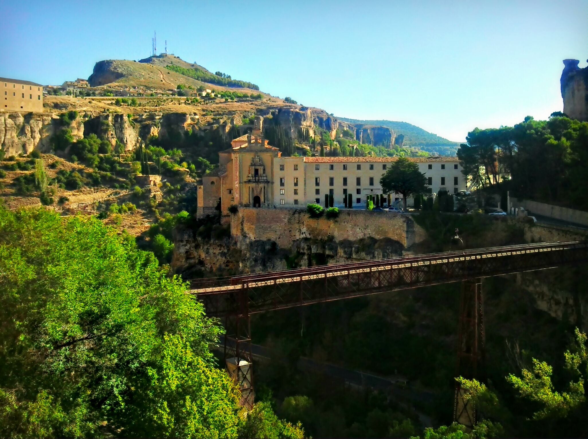 A bridge over a canyon with buildings on a hillside.