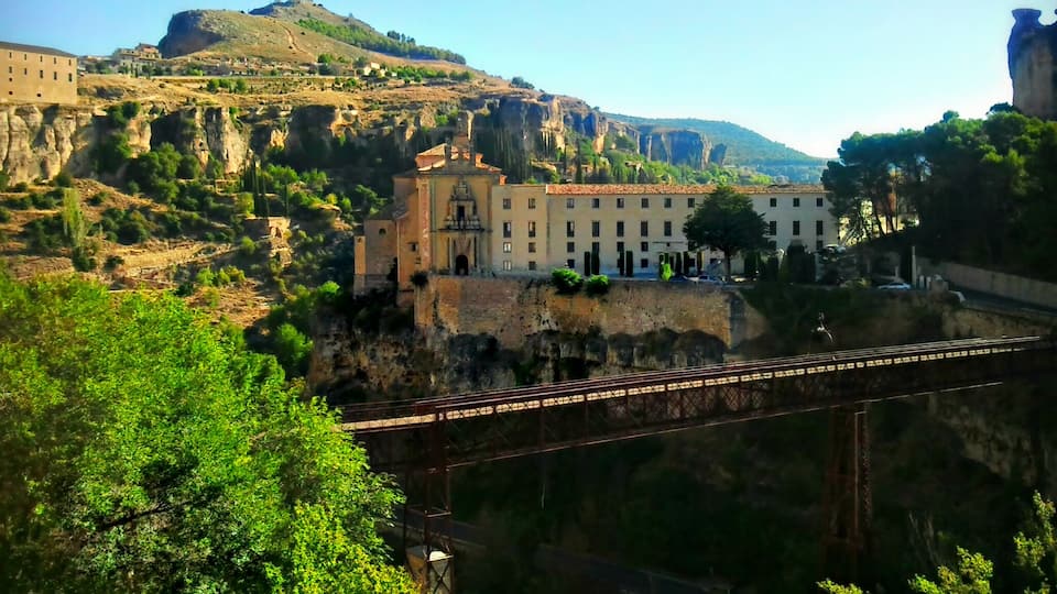 A bridge over a canyon with buildings on a hillside.