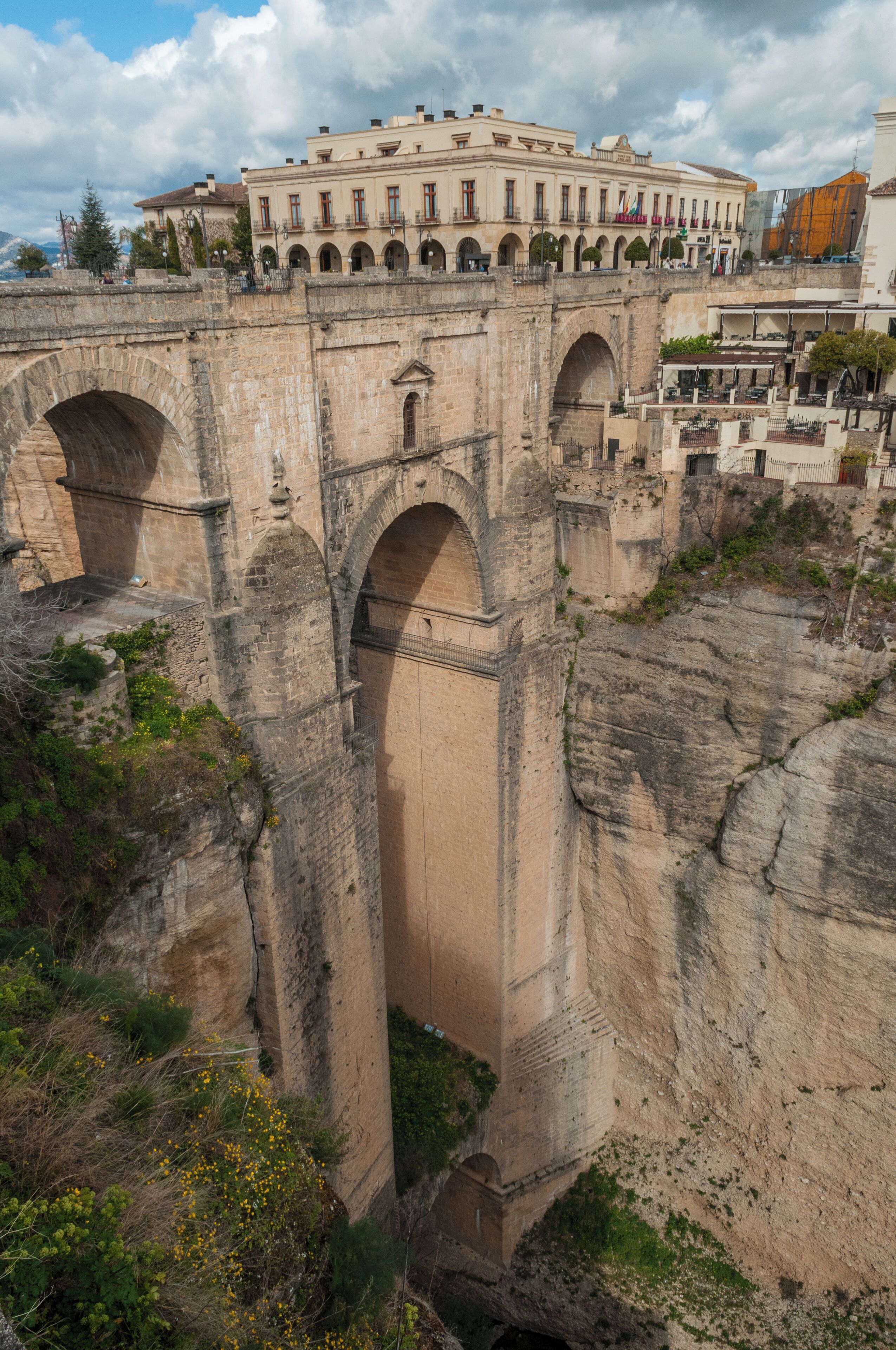 The Puente Nuevo is the newest and largest of three bridges that span the 120-metre (390 ft)-deep chasm that carries the Guadalevín River and divides the city of Ronda, in southern Spain. The architect was José Martin de Aldehuela, who died in Málaga in 1802. The chief builder was Juan Antonio Díaz Machuca. The bridge was built in 1751 and took a total of 42 years to build and claimed the lives of 50 builders. There is a chamber beneath the central arch that was used for a variety of purposes, including as a prison. During the civil war (1936 to 1939), both sides allegedly used the prison as a torture chamber for captured opponents, killing some by throwing them from the windows to the rocks below at the bottom of the El Tajo gorge. One enters the chamber via a square building that was once the guard-house. It contains an exhibition describing the bridge's history and construction. The bridge is supposedly one of the most photographed structures in Spain. Puente Nuevo. (2012, March 20). In Wikipedia, The Free Encyclopedia. Retrieved 19:14, April 14, 2012, from en.wikipedia.org/w/index.php?title=Puente_Nuevo&oldid...
