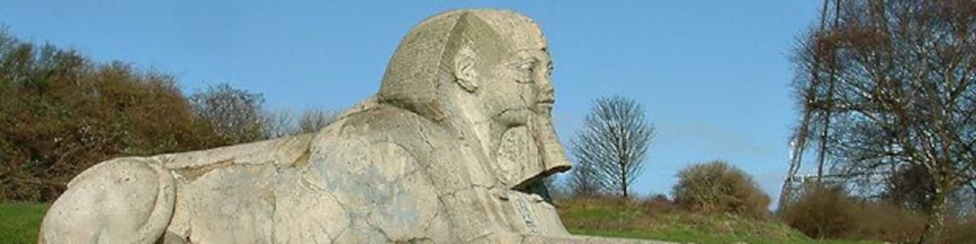 A stone sphinx statue with a rocket tower in the background.