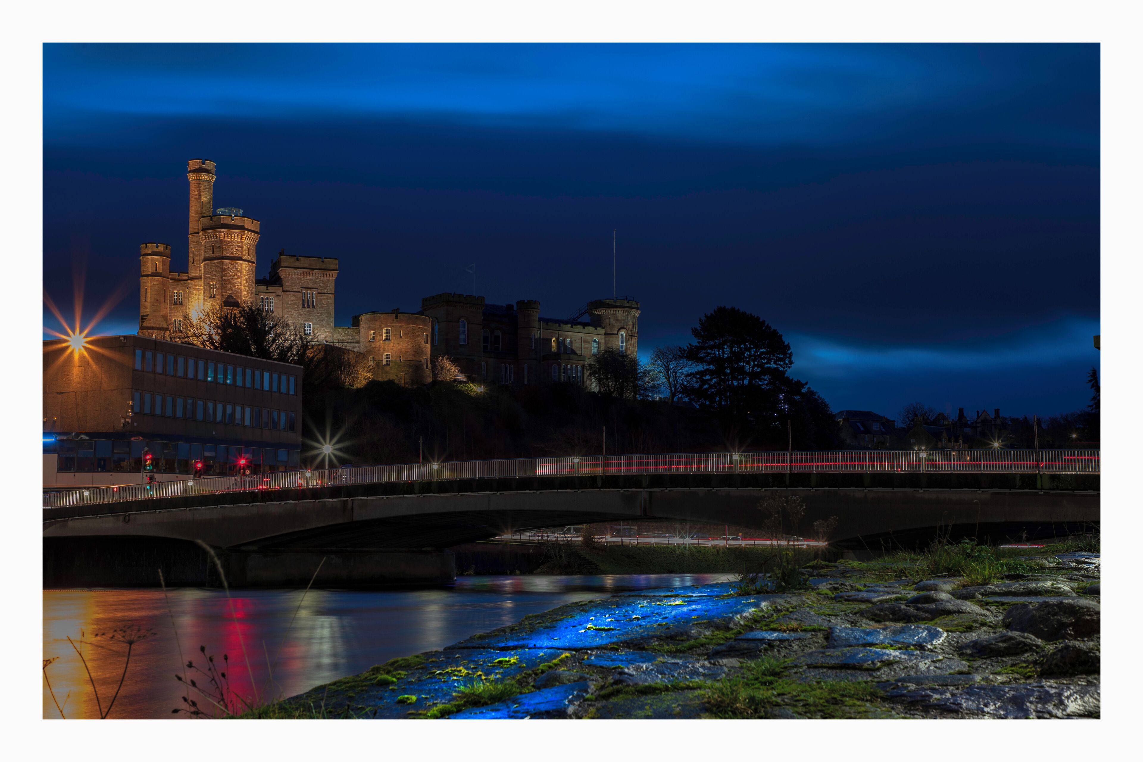 Un castillo por la noche con un puente sobre un río.
