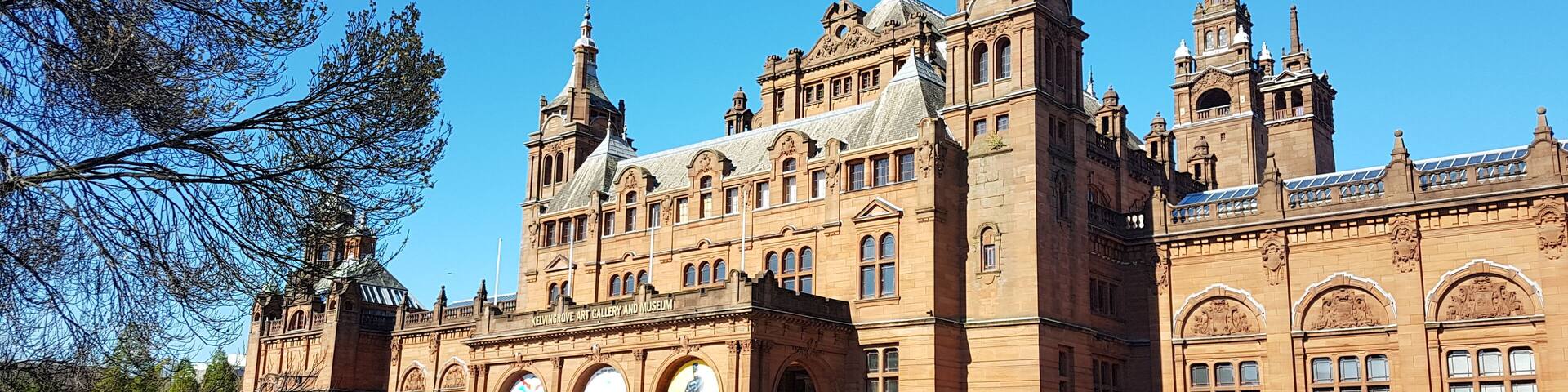 A large, historic building with intricate architecture, surrounded by a well-maintained garden and pathways.