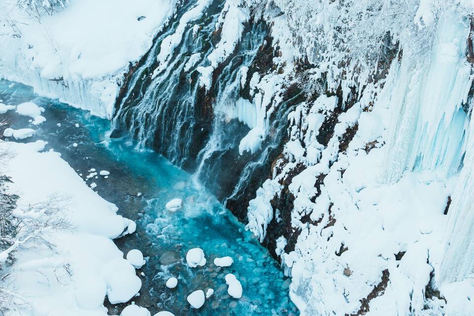 Un gegant de gel que sembla una cascada, envoltat d'arbres coberts de neu.