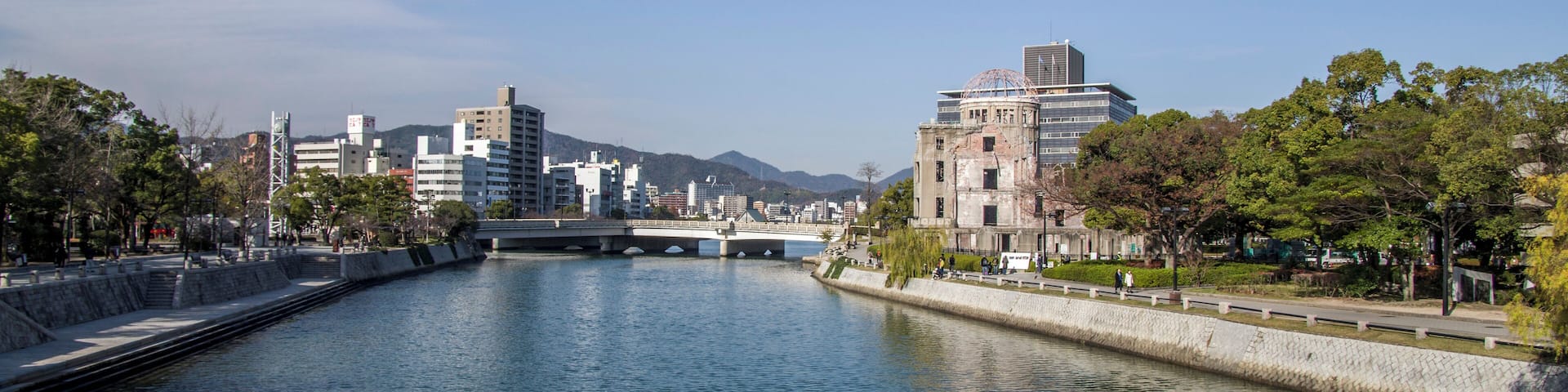A river with a bridge, buildings, and trees.