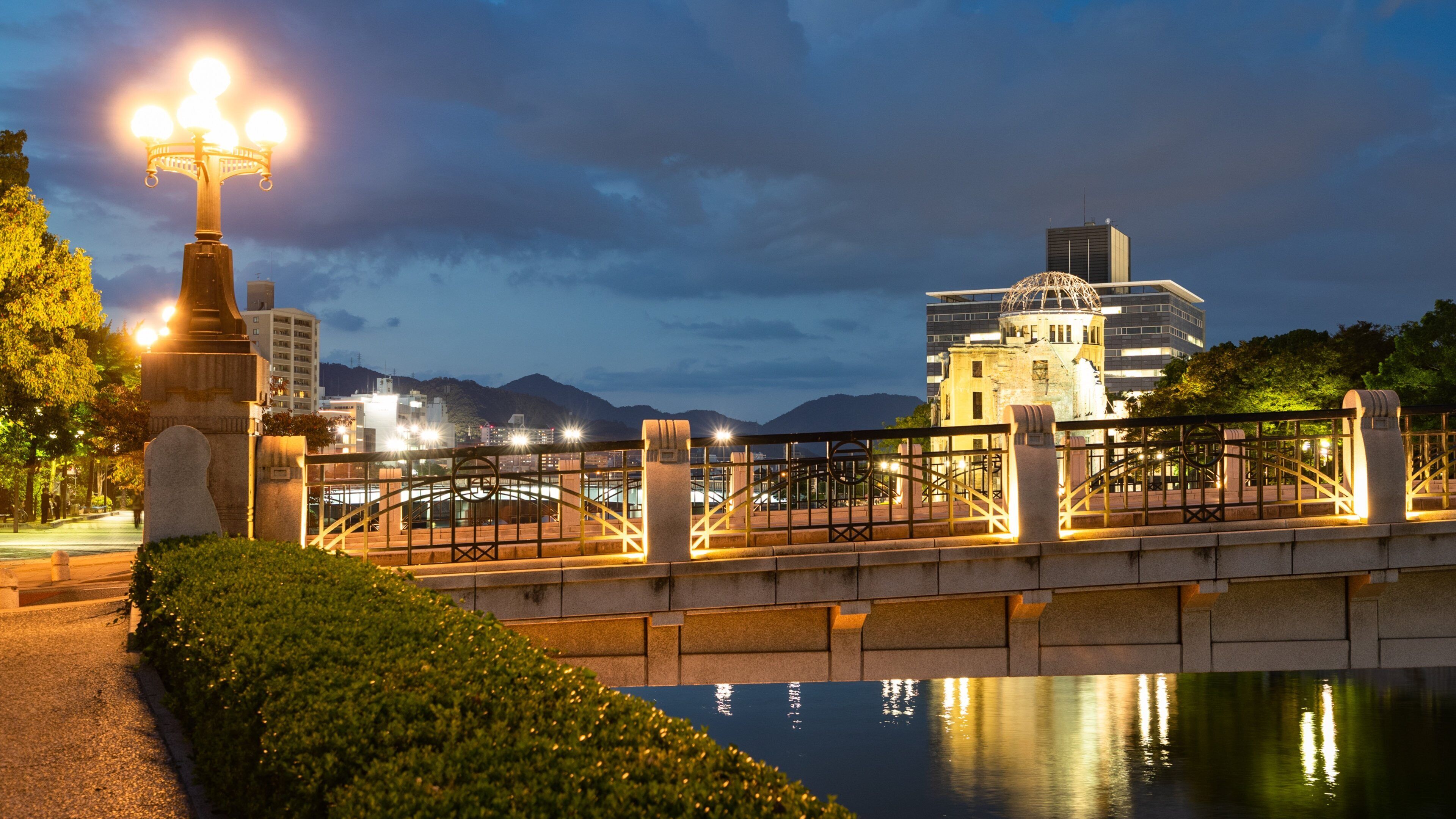 A bridge with a stone balustrade, a stone monument, and a building with a dome in the background.
