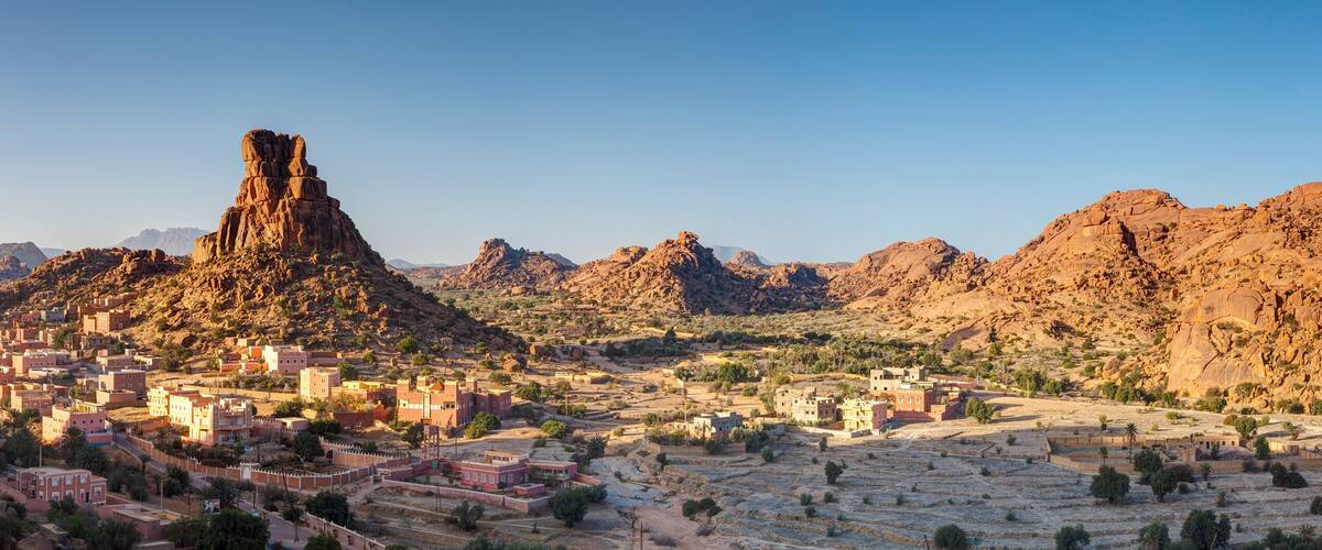 A town nestled in a rocky desert landscape with a prominent rock formation in the center.