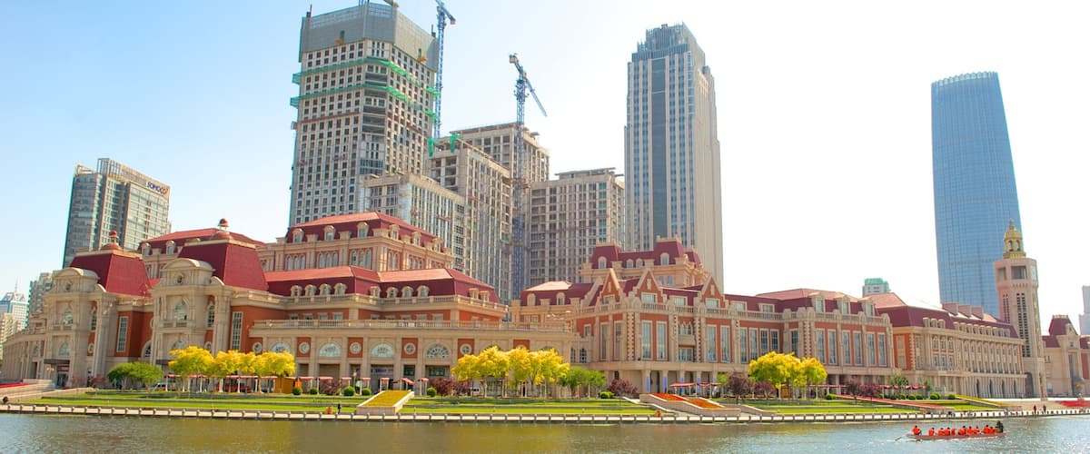 A historic building with red roofs and yellow trees in front, surrounded by modern skyscrapers.