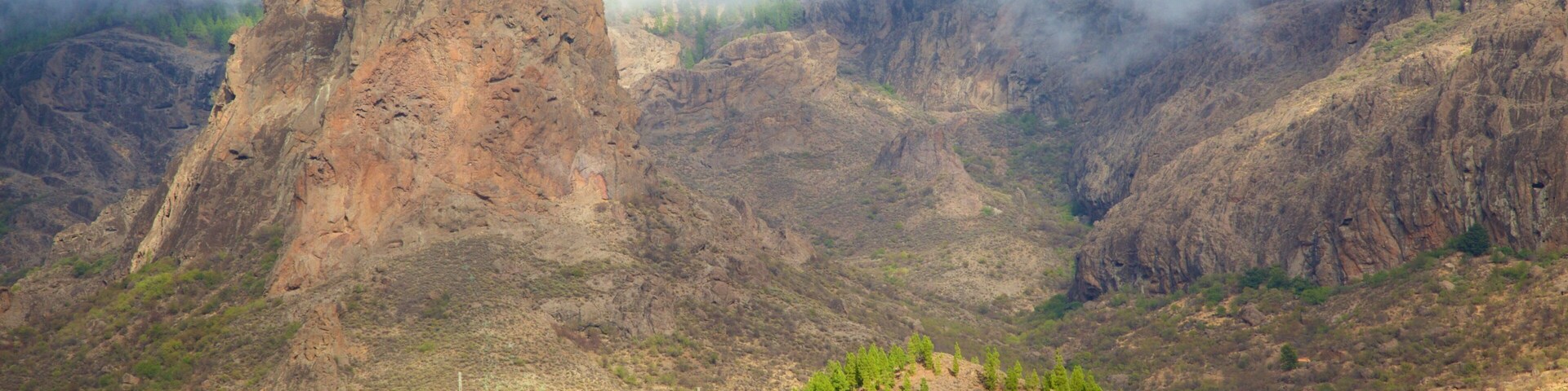 A rugged mountain landscape with a prominent rocky peak and sparse vegetation.