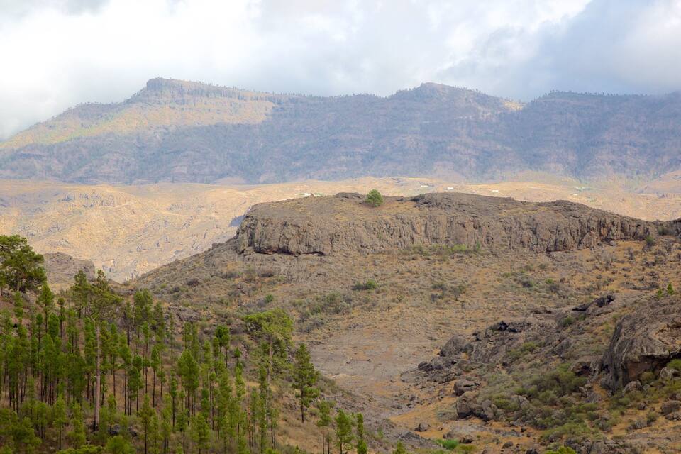 A rugged mountainous landscape with sparse vegetation and a rocky terrain.