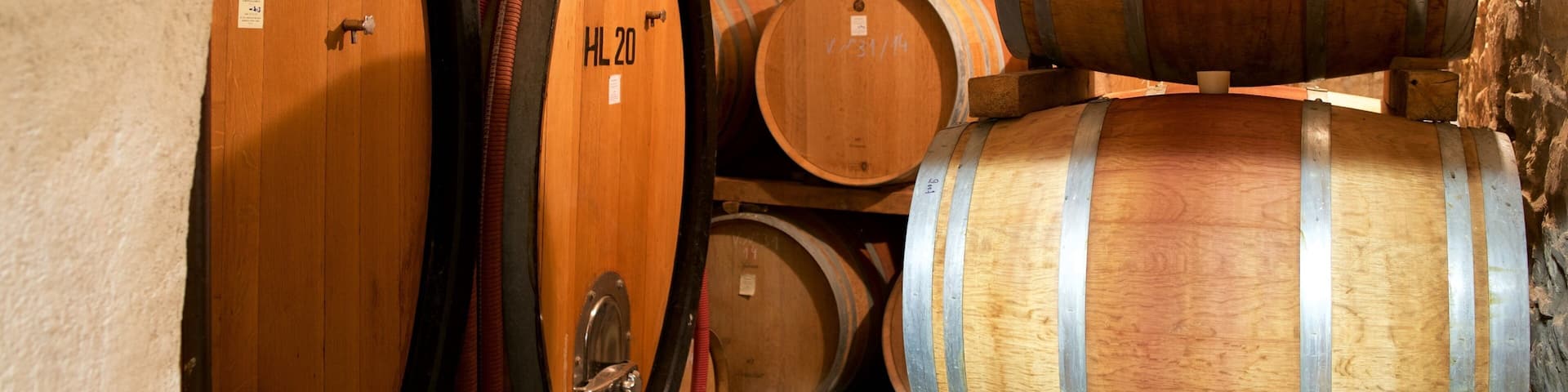 Barricas de madera apiladas en una bodega con paredes de piedra.