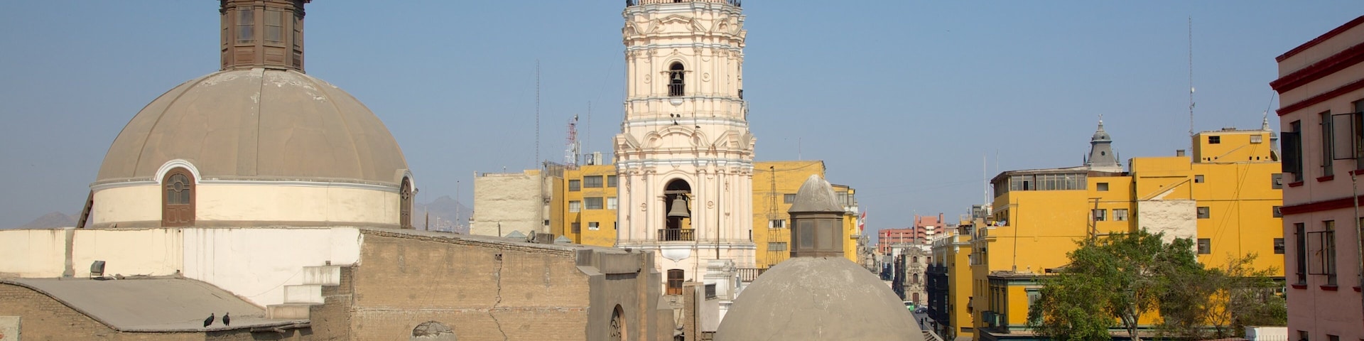 Um edifício histórico com uma torre de sino e cúpula, rodeado por edifícios urbanos.