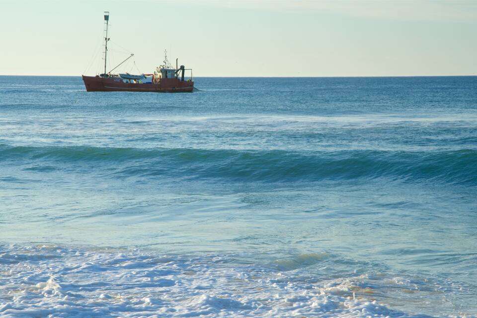 A large fishing boat on calm ocean waters with gentle waves.