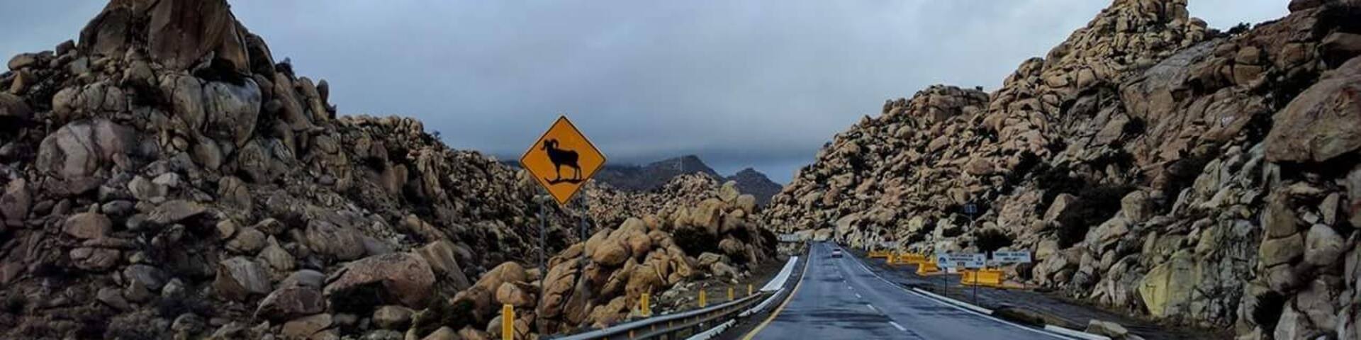 A road flanked by large rocks under a cloudy sky.