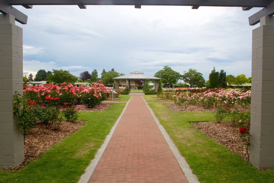 A garden pathway leading to a gazebo surrounded by flower beds.