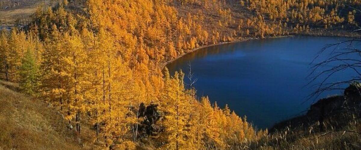 A lake surrounded by autumn-colored trees and rolling hills.