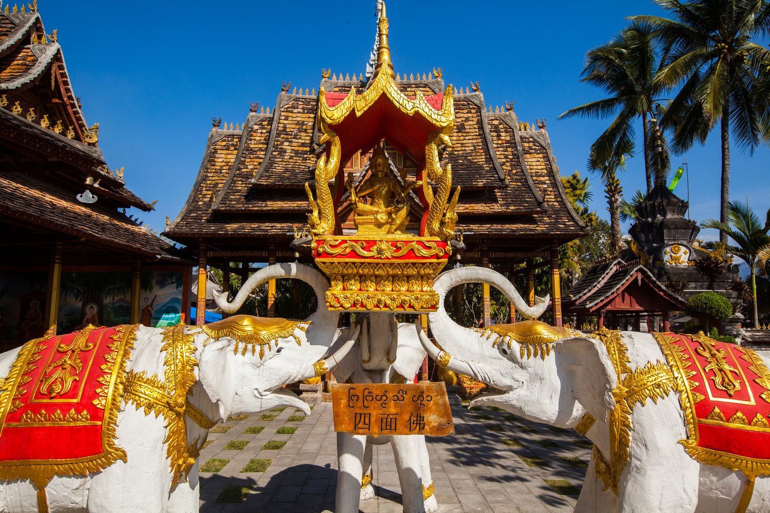 A temple with a golden roof and a white elephant statue.