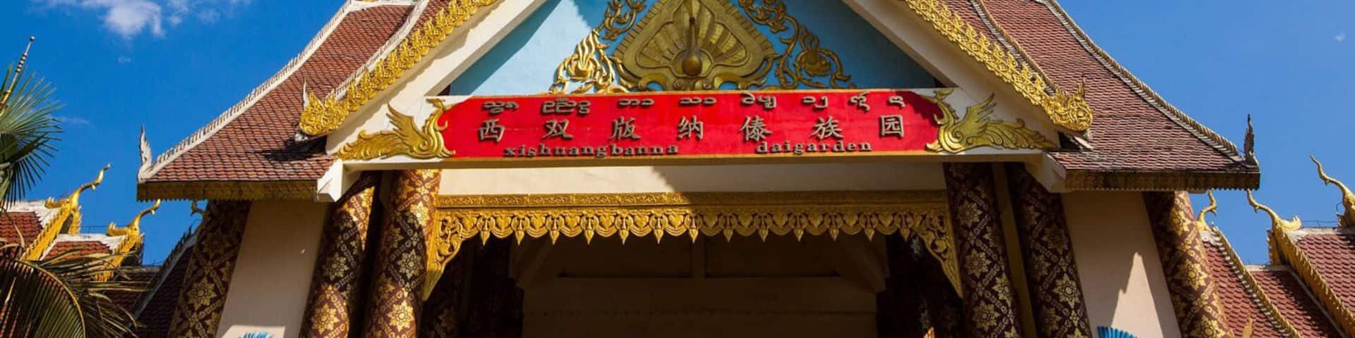 A traditional Thai temple with ornate golden decorations and a red banner with white text.
