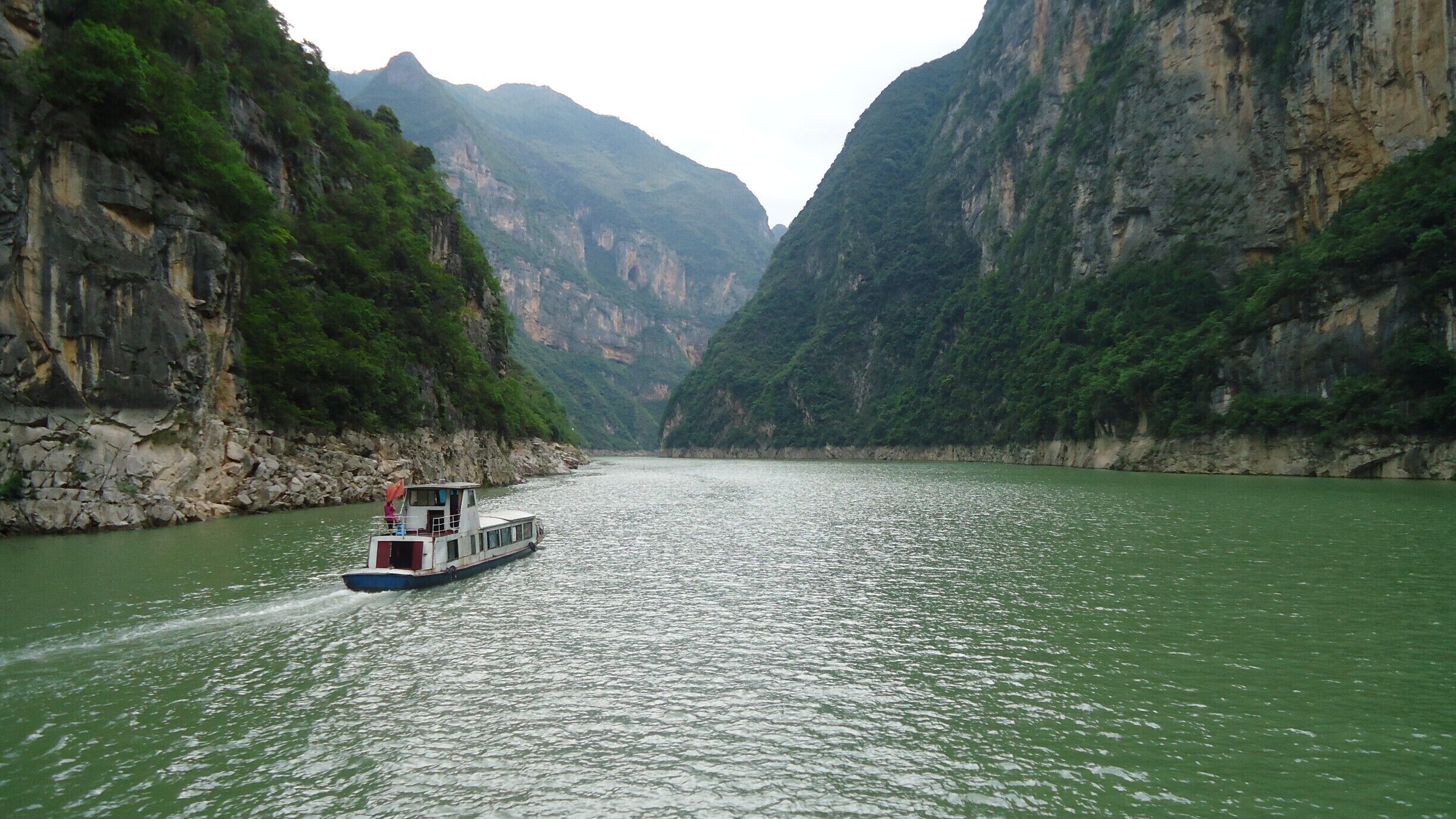A boat on a river surrounded by steep, rocky cliffs.