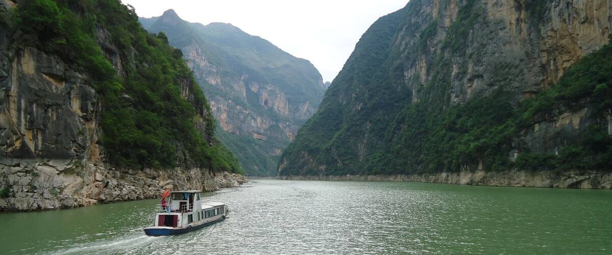 A boat on a river surrounded by steep, rocky cliffs.
