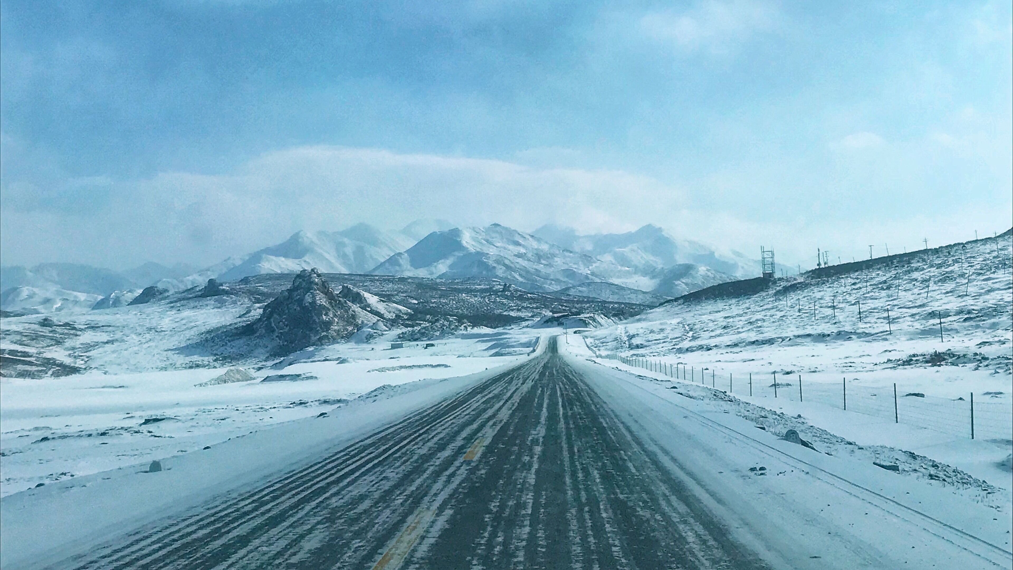 A snow-covered road with mountains in the background.