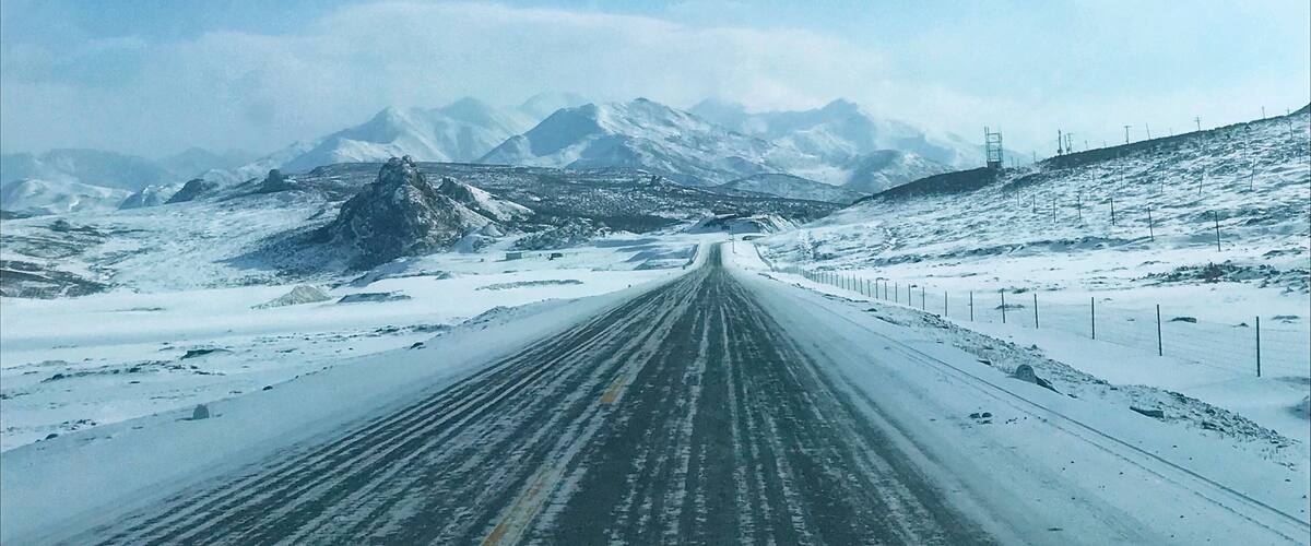 A snow-covered road with mountains in the background.