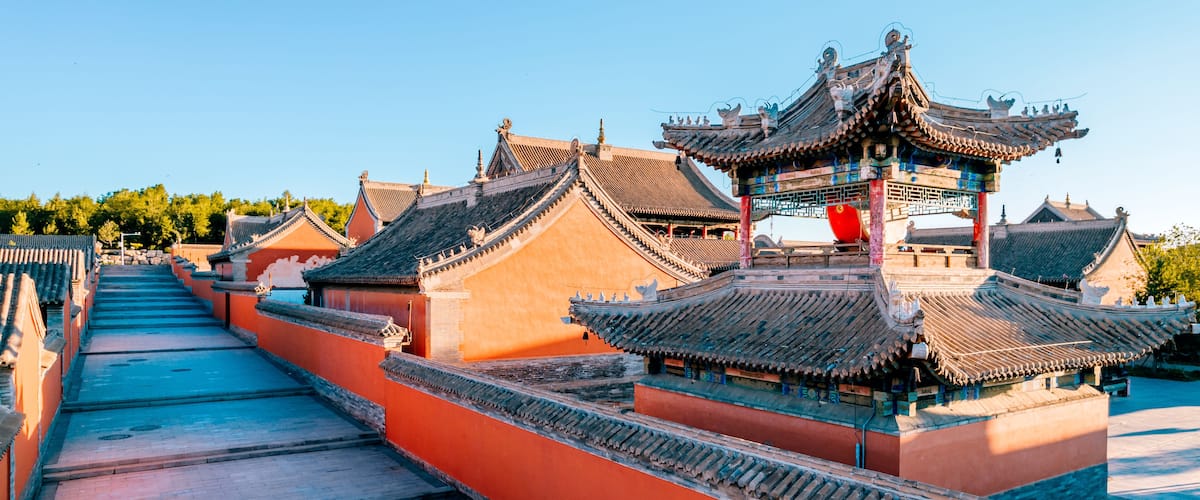 Traditional Chinese architecture with ornate roofs and a red wall.