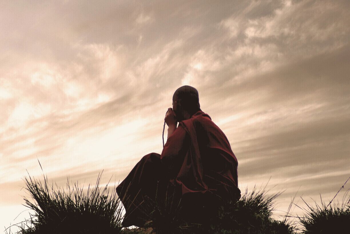 Monk praying in the grassland surrounding the monastery.