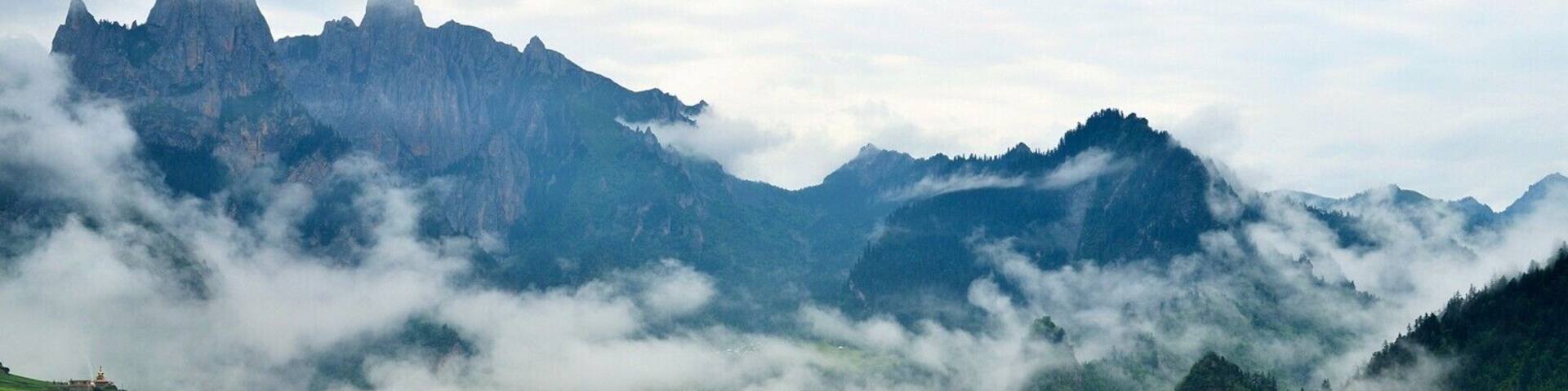 A mountainous landscape with terraced fields, a prominent peak, and a village nestled in the valley.