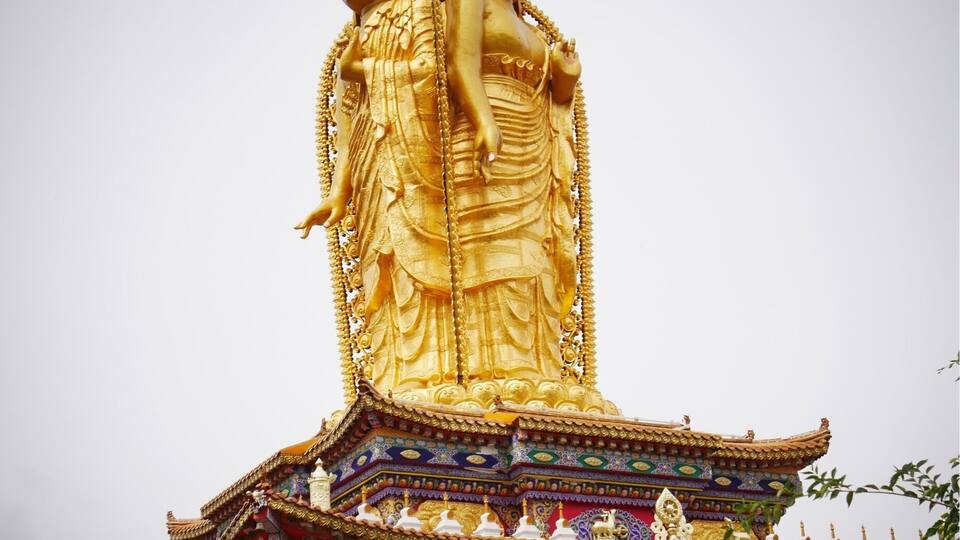 A large golden statue of a deity atop a colorful temple roof.