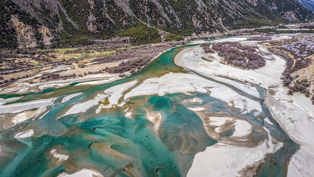 A river with clear turquoise water flowing through a mountainous landscape.