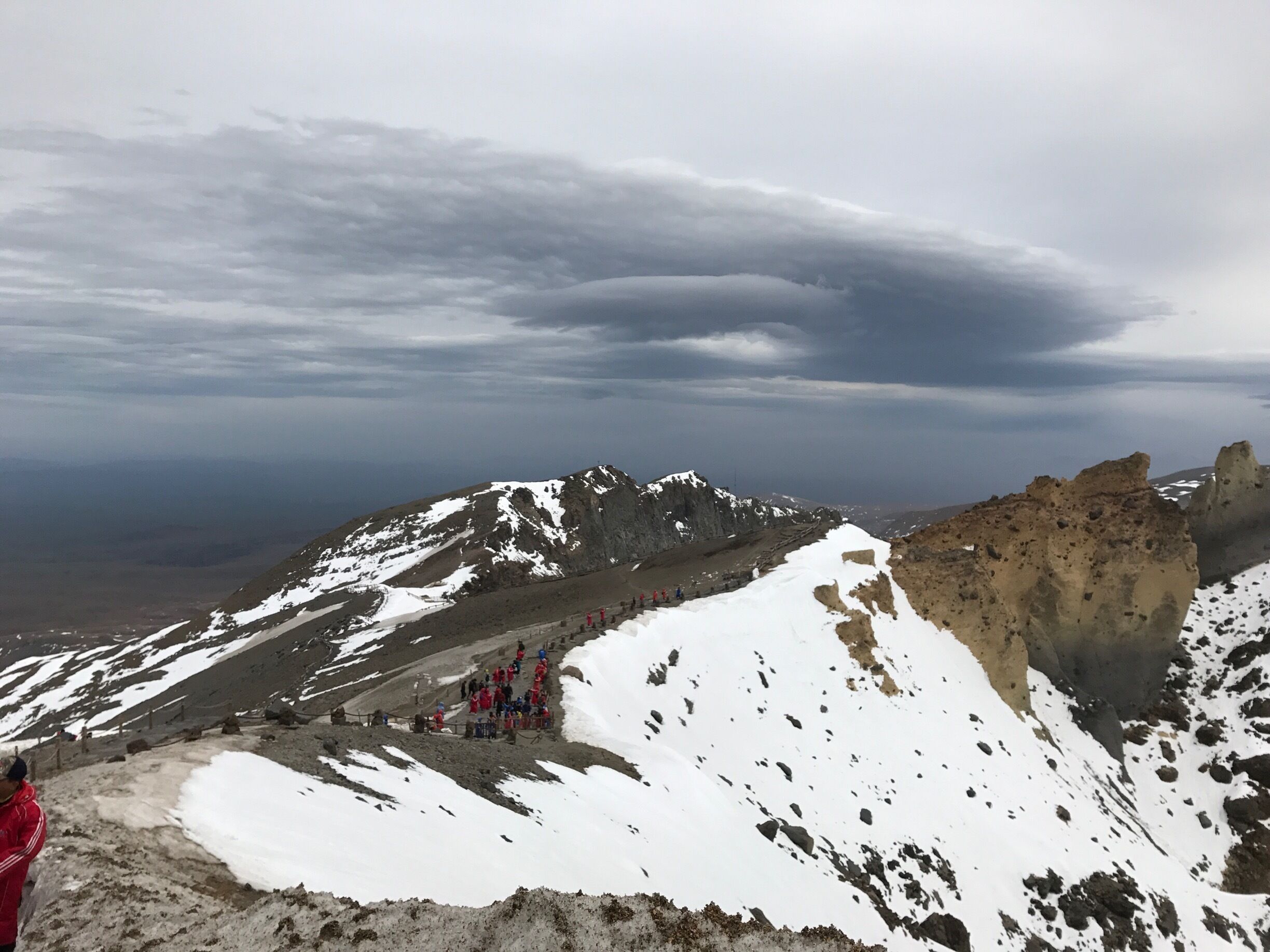 A snowy mountain landscape with a group of hikers in red jackets.