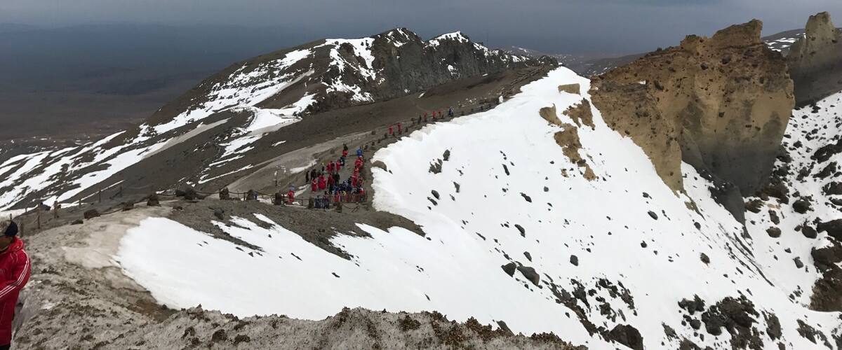 A snowy mountain landscape with a group of hikers in red jackets.