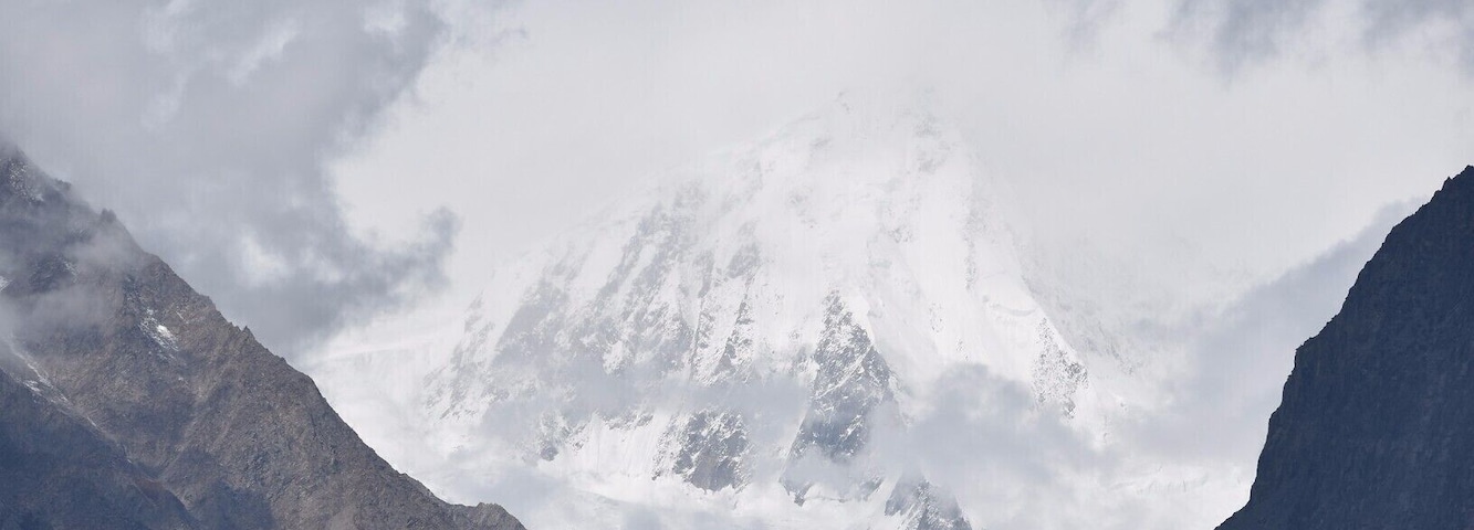 Um glaciar com picos cobertos de neve ao fundo.