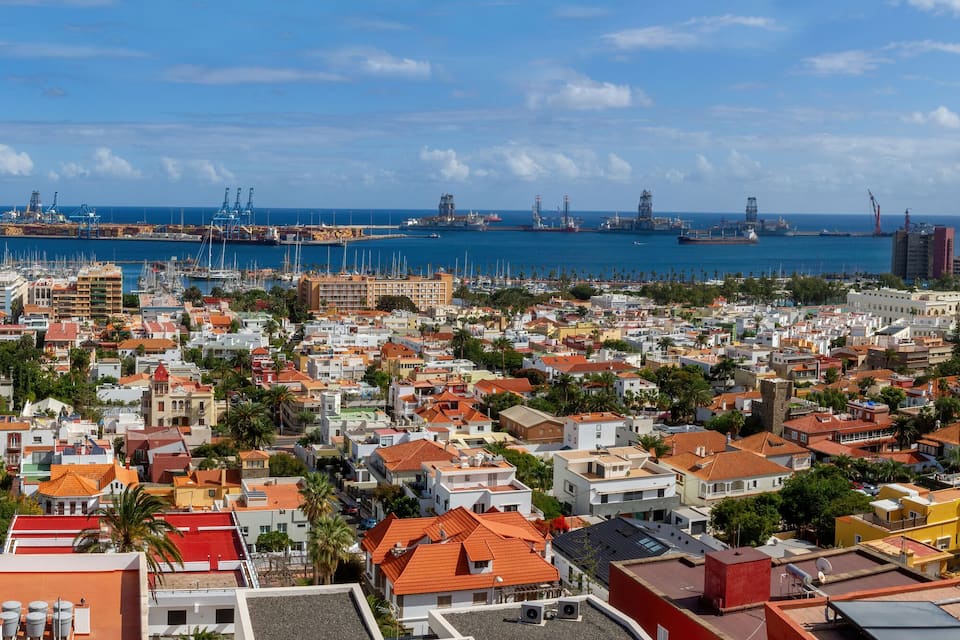 A coastal cityscape with a marina, industrial port, and dense urban buildings.