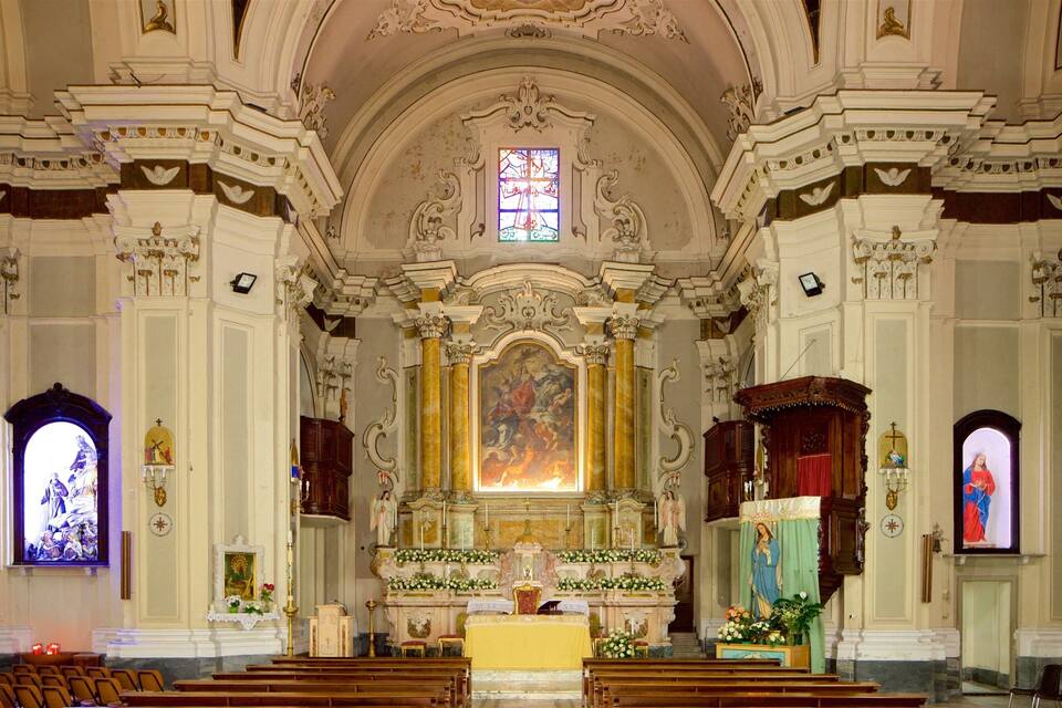 Interior de igreja ornamentado, com altar central, vitrais e decoração de teto elaborada.