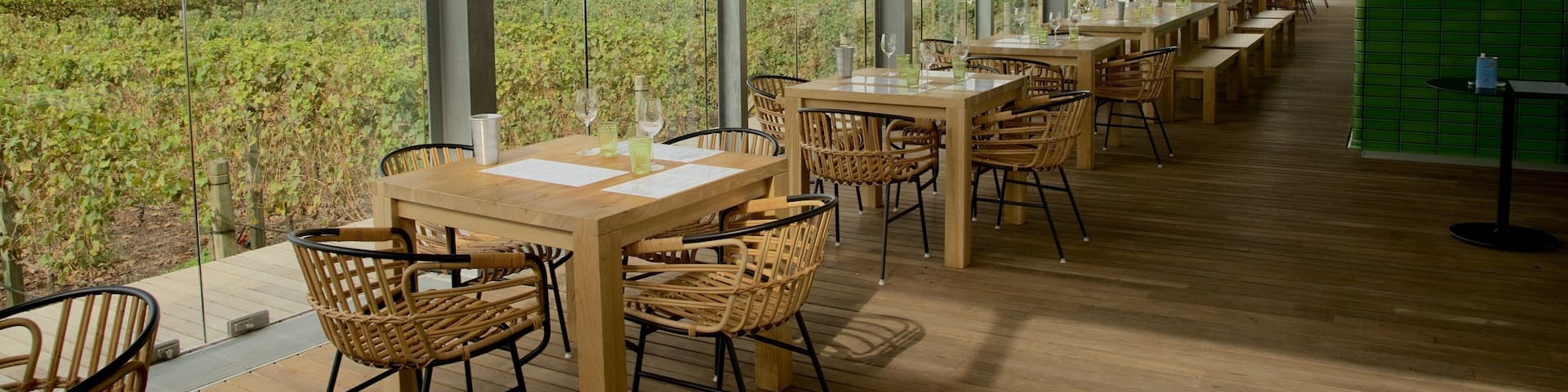 A restaurant with outdoor seating overlooking a vineyard and a mountain.