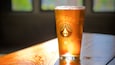 Un verre de bière avec un logo en forme de crâne, posé sur une table en bois.