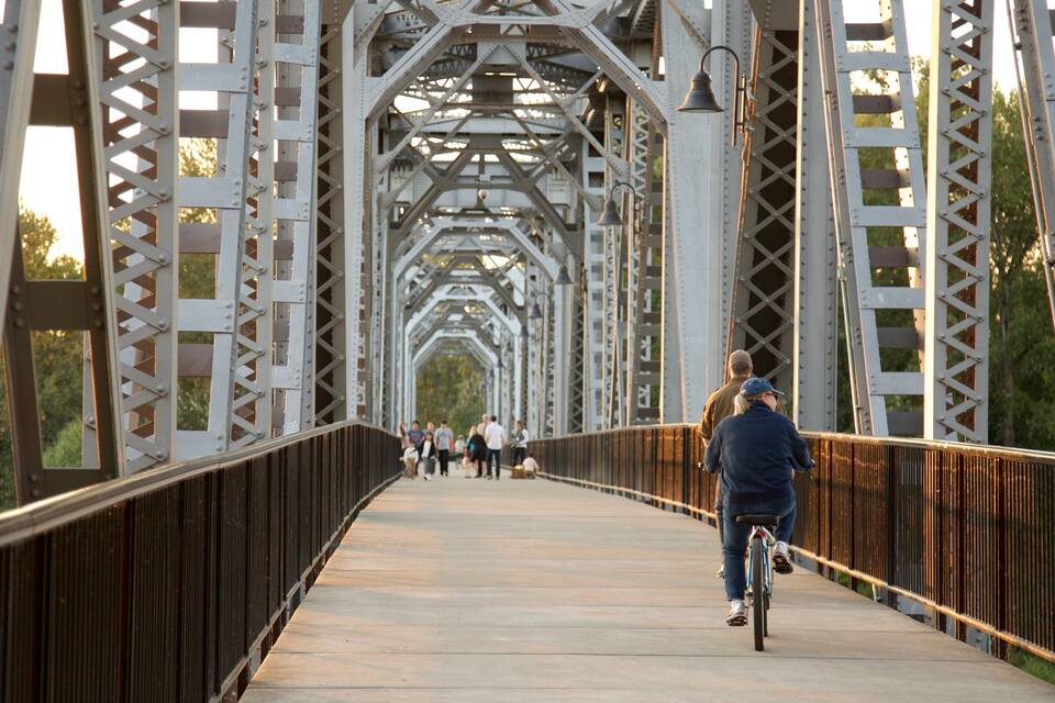 A metal bridge with a pedestrian walkway and a cyclist.