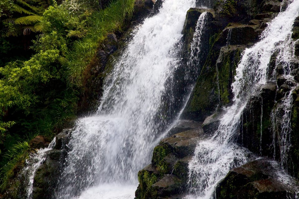 Ein mehrstufiger Wasserfall, umgeben von üppigem Grün.