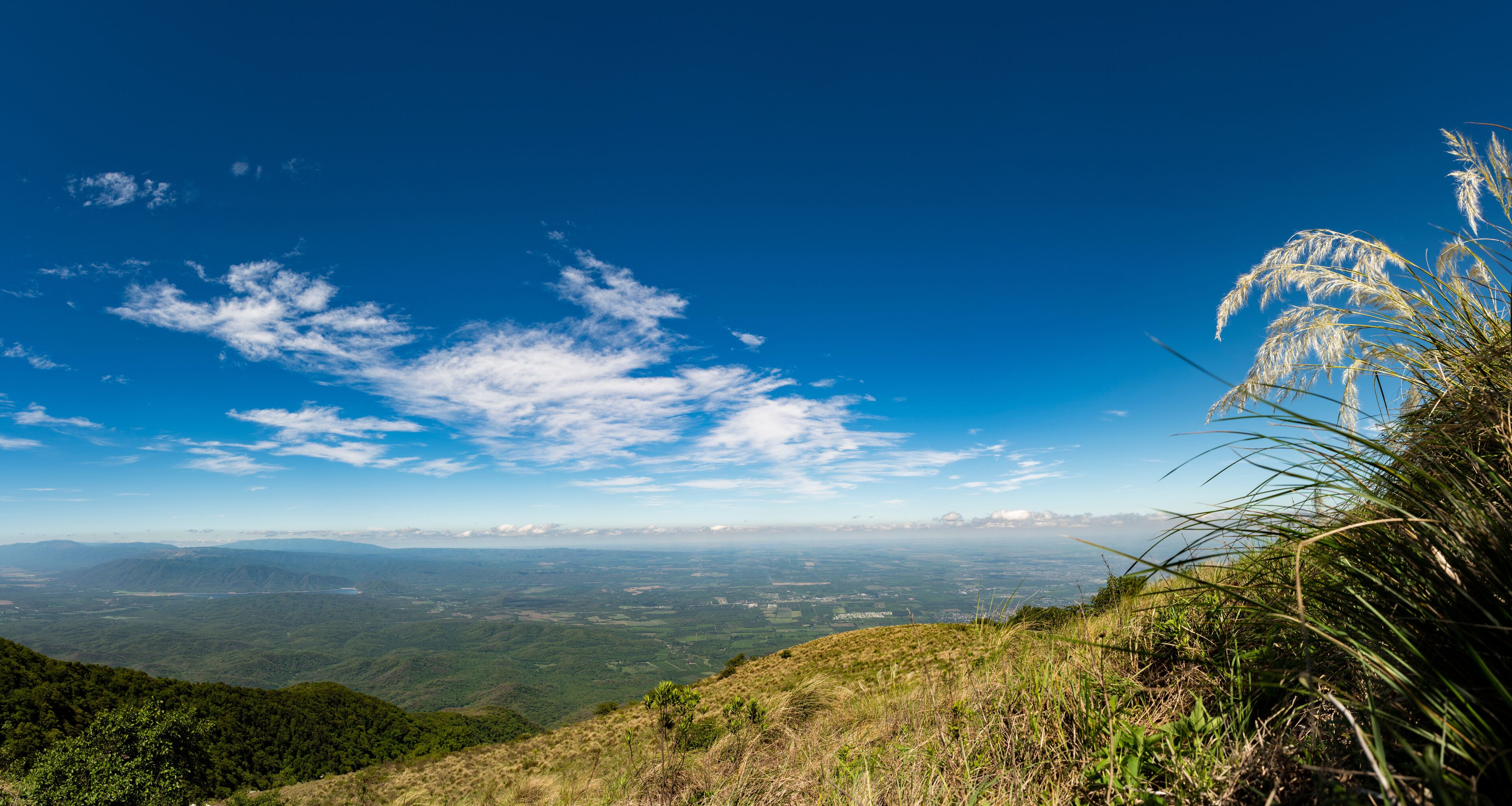 A mountainous landscape with a clear blue sky and scattered clouds.