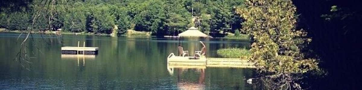 A calm lake with a dock and a gazebo.