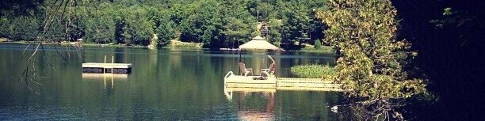 A calm lake with a dock and a gazebo.