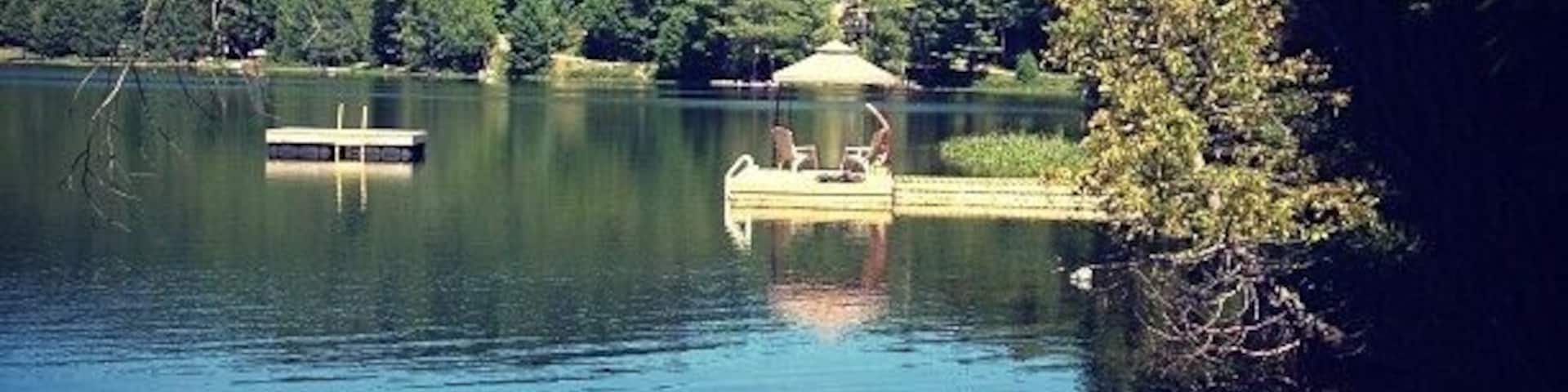 Un lago tranquilo con un muelle y un pabellón.
