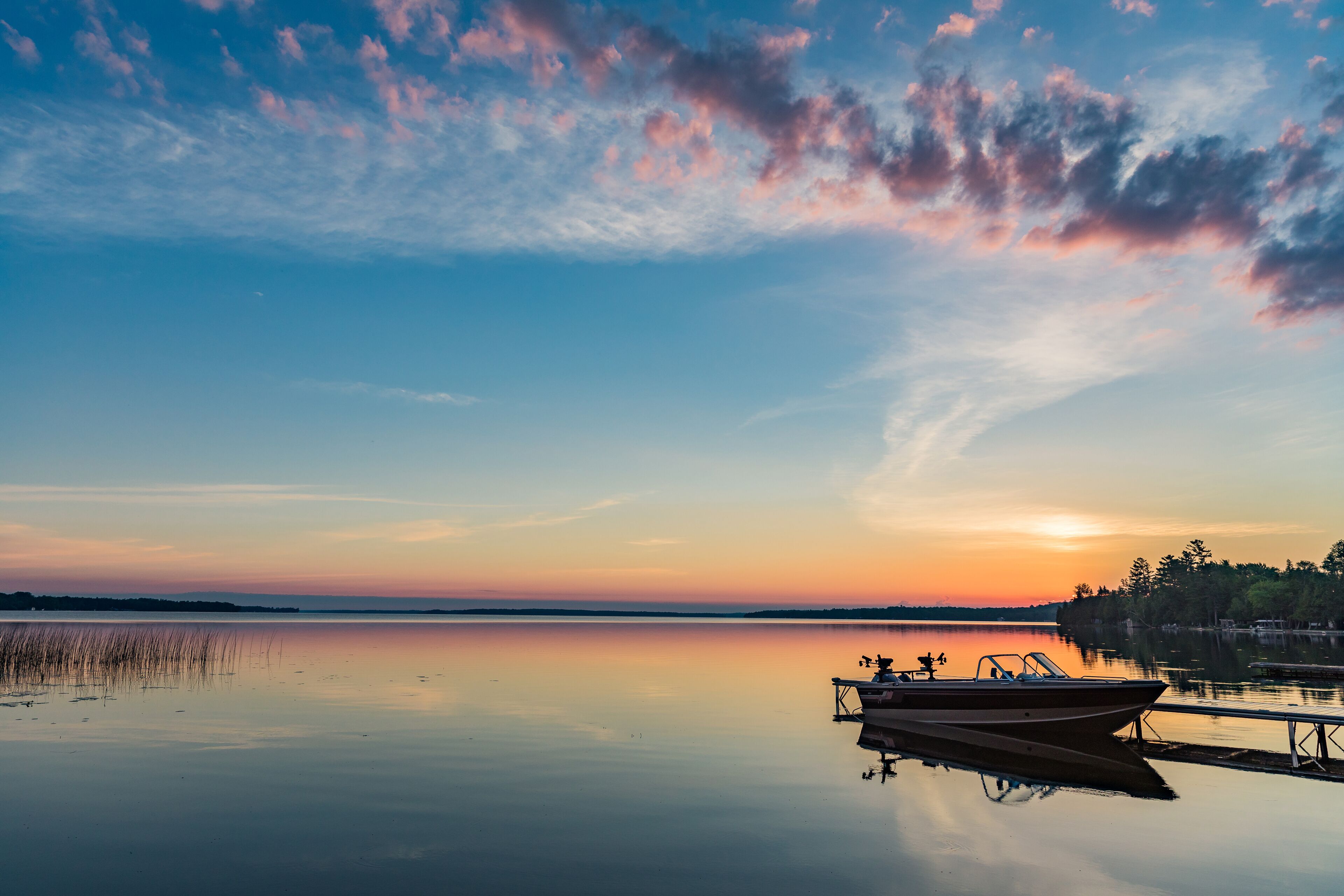 Cottage vacation holiday with a beautiful early sunrise overlooking the fishing boat and dock in Canada, Balsam Lake in Kawartha Lakes 