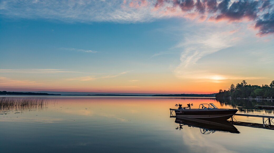 Cottage vacation holiday with a beautiful early sunrise overlooking the fishing boat and dock in Canada, Balsam Lake in Kawartha Lakes