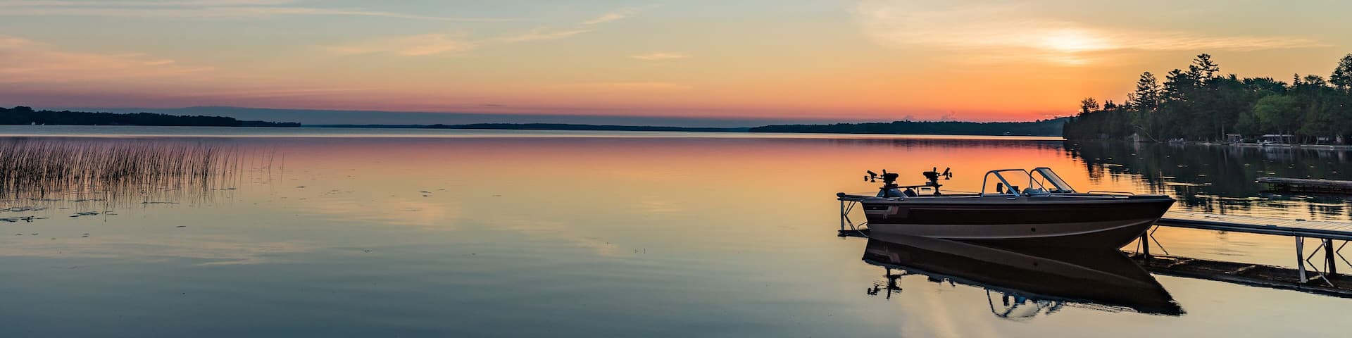Cottage vacation holiday with a beautiful early sunrise overlooking the fishing boat and dock in Canada, Balsam Lake in Kawartha Lakes