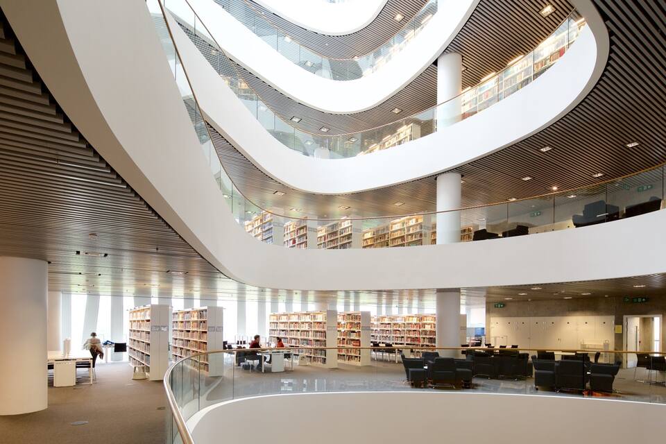 Eine moderne, mehrgeschossige Bibliothek mit gewölbten Decken und Glasgeländern.
